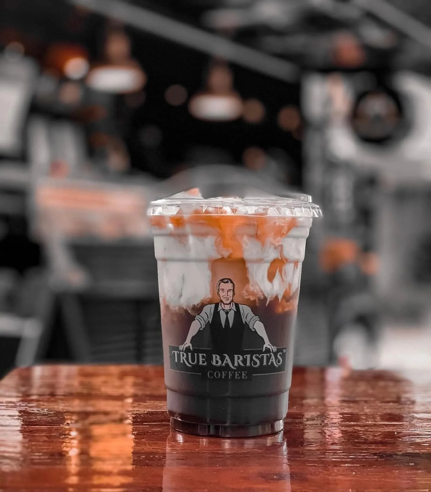 A layered iced coffee in a True Baristas branded cup